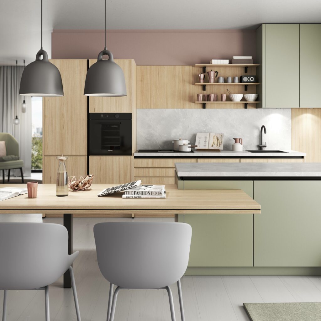 Modern kitchen with light wood and green cabinets, a built-in oven, and open shelves displaying tableware. The benefits of colour diversity are highlighted by the vibrant green accents. Features a dining area with a wooden table, grey chairs, and pendant lights.