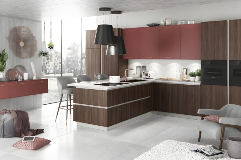 Modern kitchen with wood and red cabinetry, island with bar stools, black pendant lights, and various kitchen appliances showcasing the latest kitchen design trends for home cooks. A cozy seating area with a chair and tablet is adjacent. Large windows in the background complete the look.