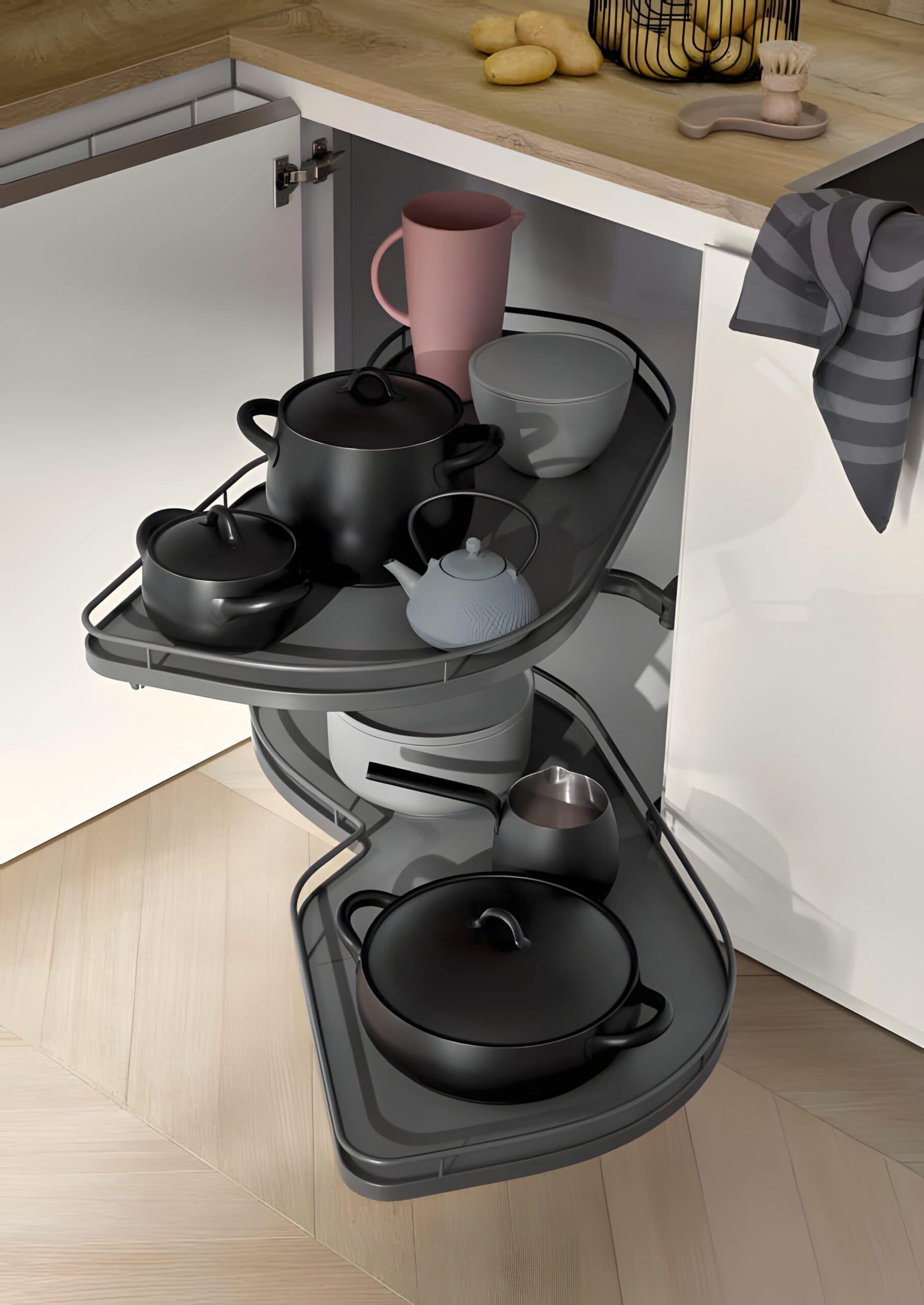 A corner kitchen cabinet with pull-out shelves featuring various black and gray pots, bowls, and a pink jug. The cabinet is open, displaying the organized kitchenware, offering eco-friendly organization ideas for kitchen cabinets.