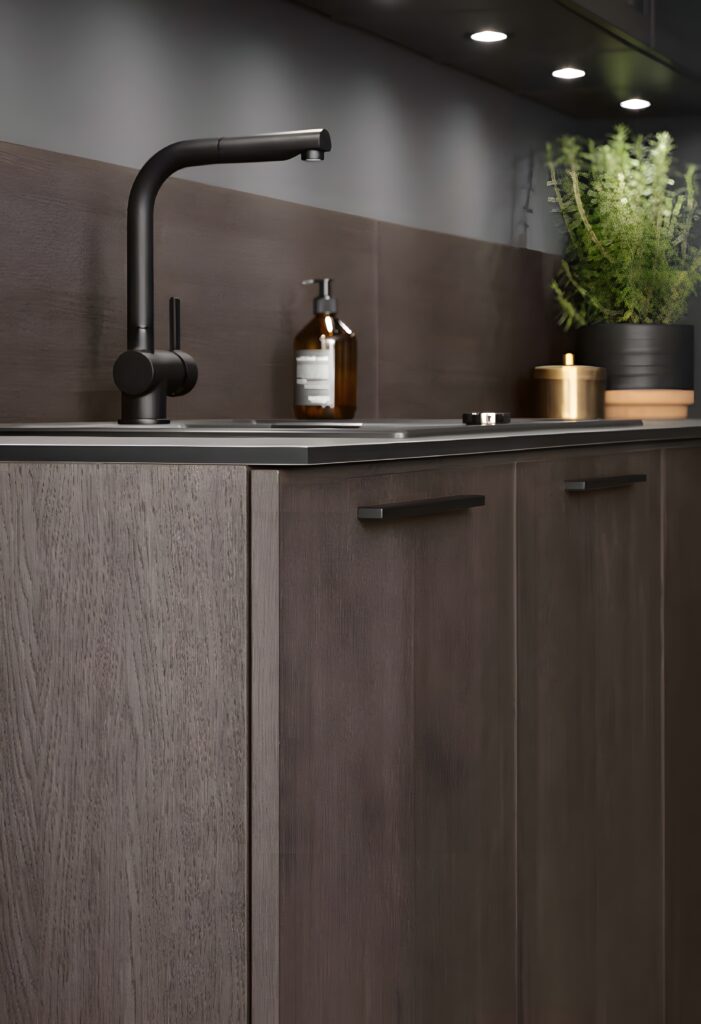 A modern kitchen sink with a matte black faucet is set against dark wooden cabinets, showcasing modern innovations in German kitchen design. A potted plant, hand soap, and jar are thoughtfully placed on the countertop.