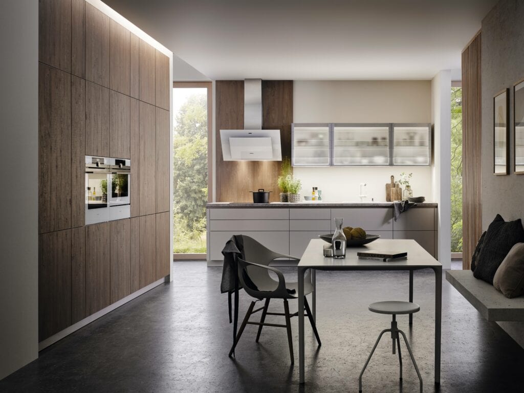 Modern kitchen with clean lines featuring wooden German kitchen cabinets, integrated appliances, and a dining area with minimalist furniture, embodying green benefits.