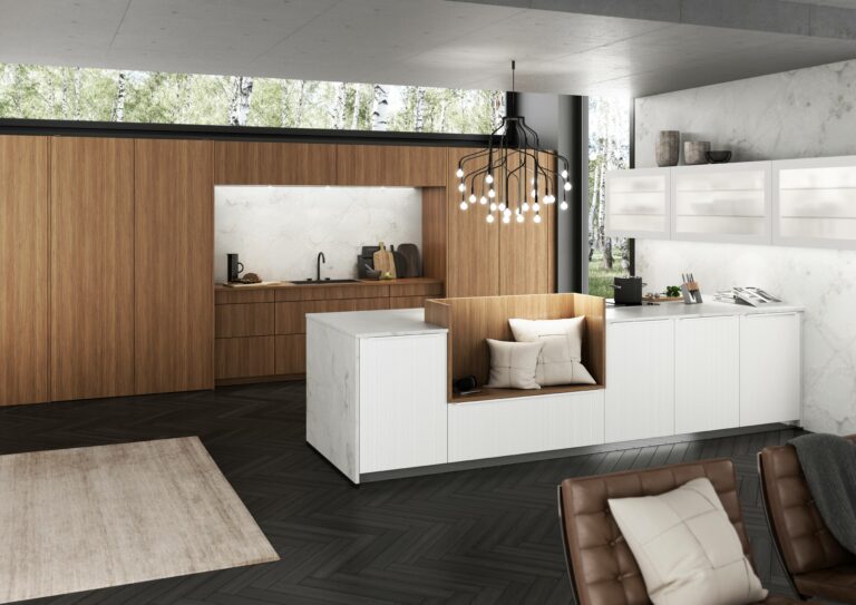 Modern kitchen with a blend of wood and white cabinetry, featuring an island with built-in seating and space-saving kitchen furniture. Minimalist decor complements the large window with a forest view, while a black chandelier hangs from the ceiling.