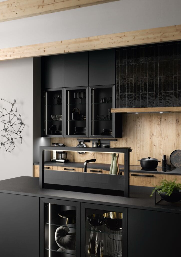Modern kitchen with black cabinets, light wooden accents, built-in appliances, and a minimalist island counter with a glass partition. This minimalist kitchen design features geometric wall art on the left wall.