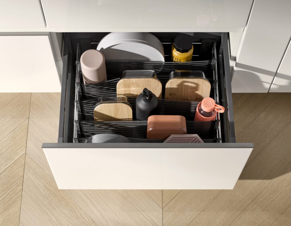 A kitchen drawer with dividers, featuring smart storage solutions, organizes various food containers, jars, and bottles in an orderly manner.